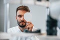 Covering right eye. Man is checking his vision indoors in the clinic Royalty Free Stock Photo