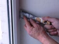 Old spatula in man`s hands filling the window slope