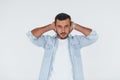 Covers his ears. Young handsome man standing indoors against white background Royalty Free Stock Photo