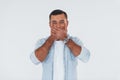 Covers his mouth. Young handsome man standing indoors against white background Royalty Free Stock Photo