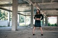 A coveted woman or girl stands in the middle of an abandoned building in a leather skirt top and sunglasses, brunette