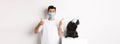 Covid-19, animals and quarantine concept. Young man and black dog wearing medical masks, pug looking at upper left Royalty Free Stock Photo