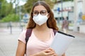 COVID-19 Beautiful student female with protective mask walking in city street. College young woman back to school after pandemic Royalty Free Stock Photo