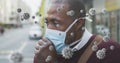 Covid-19 cells floating against african american senior man wearing face mask couching