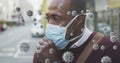 Covid-19 cells floating against african american senior man wearing face mask couching Royalty Free Stock Photo