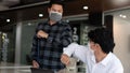 Covid-19 concept Coronavirus two male colleagues wearing protective face masks greeting bumping elbows at office protecting from Royalty Free Stock Photo