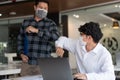 Covid-19 concept Coronavirus two male colleagues wearing protective face masks greeting bumping elbows at office protecting from Royalty Free Stock Photo