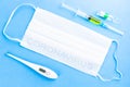 COVID-19 concept picture with medical face masks, digital thermometer with high temperature, pills and syringe on the blue Royalty Free Stock Photo