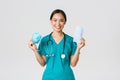 Covid-19, coronavirus disease, healthcare workers concept. Smiling pretty asian female nurse, physician in scrubs Royalty Free Stock Photo