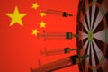 COVID-19 coronavirus disease vaccine syringes hit target against the Chinese flag. Successful research and vaccination