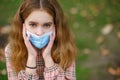 COVID-19 Coronavirus pandemic girl child in a city park wearing a mask protecting against the spread of the SARS-CoV-2 virus Royalty Free Stock Photo