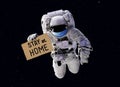 COVID-19 coronavirus quarantine concept, funny astronaut wearing medical mask in outer space with slogan Stay at Home on cardboard