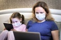 COVID-19 coronavirus quarantine concept, woman in face mask working with laptop staying home. Mother and child using computers Royalty Free Stock Photo