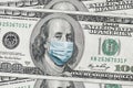 COVID-19 coronavirus in USA. Hundred golden dollar money bill with face mask.