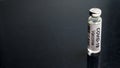 COVID-19 coronavirus vaccine background, bottle with vaccine for SARS-CoV-2 coronavirus cure on black desk