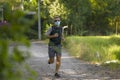 Covid-19 deconfinement - young attractive and happy man outdoors in city park doing running workout wearing protective face mask Royalty Free Stock Photo