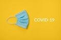COVID-19 disposable surgical face mask on yellow background