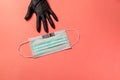 Covid-19. Doctor hand in black protective glove, points out surgical mask with copy space on pink background. Royalty Free Stock Photo