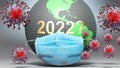 2022 and covid - Earth globe protected with a blue mask against attacking corona viruses to show the relation between 2022 and