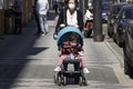 Covid-19 female with toddler in push chair both wearing facial masks strolling in the spring sun in Prague Europe