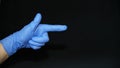 COVID-19 Hand with blue surgical glove pointing right direction, on black Royalty Free Stock Photo