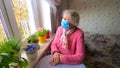 The Covid-19, health, safety and pandemic concept - senior old lonely woman sitting near the window Royalty Free Stock Photo