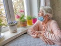 The Covid-19, health, safety and pandemic concept - senior old lonely woman sitting near the window Royalty Free Stock Photo