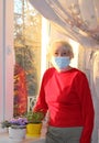 The Covid-19, health, safety and pandemic concept - senior old lonely woman sitting near the window Royalty Free Stock Photo