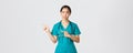 Covid-19, healthcare workers, pandemic concept. Skeptical and doubtful pretty asian doctor, nurse in scrubs smirk Royalty Free Stock Photo