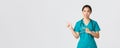 Covid-19, healthcare workers, pandemic concept. Skeptical and doubtful pretty asian doctor, nurse in scrubs smirk Royalty Free Stock Photo