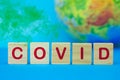 COVID inscription on wooden cubes on the background of the planet Earth and green fog. Coronavirus pandemic concept