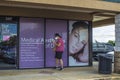 Covid-19 lady wearing a face mask on a cell phone outside of a doctors office