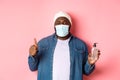 Covid-19, lifestyle and lockdown concept. Handsome african-american hipster man in face mask and beanie, showing hand Royalty Free Stock Photo