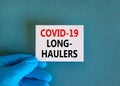 COVID-19 long-haulers covid symptoms symbol. White card with words Covid-19 long-haulers. Doctor hand, blue background, copy space Royalty Free Stock Photo