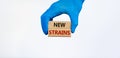 Covid-19 new strains symbol. Hand in blue glove holds wooden blocks, words `new strains`. Beautiful white background. Copy space