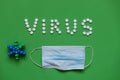 Inscription VIRUS from white pills on green background with mask medical