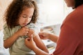 Covid nurse vaccinating child putting a bandage on at a clinic. Doctor applying plaster on girl after an injection at