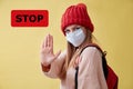 COVID-19 pandemia. Infection spread. Coronavirus outbreak. STOP red sign. Woman in medical mask show avast gesture