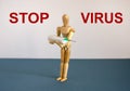 COVID-19 Pandemic Coronavirus concept. Wooden model of a man holding a syringe. Text `stop virus`. Beautiful white background