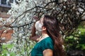 COVID-19 Pandemic Coronavirus concept. Young woman in mask smelling blossoming tree