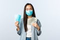 covid-19 pandemic, coronavirus expences and finance concept. Satisfied greedy asian girl in medical mask hugging money
