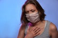 COVID-19 Pandemic Coronavirus. Girl with protective mask on face feels sick, coughs. Woman isolated on the light background