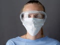 Portrait of a Nurse wearing goggles and face mask against gray background