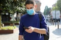 COVID-19 Pandemic Coronavirus Worried Young Man Wearing Surgical Mask Using Smart Phone App in City Street to Aid Contact Tracing Royalty Free Stock Photo