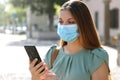 COVID-19 Pandemic Coronavirus Young Woman Wearing Surgical Mask Using Smart Phone App in City Street to Aid Contact Tracing in