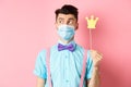 Covid, pandemic and quarantine concept. Funny man gasping amazed and looking aside in face mask, holding small party Royalty Free Stock Photo
