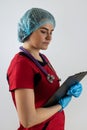 caucasian female doctor wear red uniform with stethoscope writing down patient info using clipboard Royalty Free Stock Photo