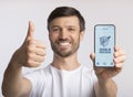 Man holding smartphone with immune health passport, showing thumbs up