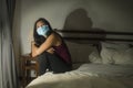 Covid-19 quarantine and home lockdown - young beautiful scared and overwhelmed Asian Chinese woman in protective mask feeling