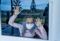 COVID-19 Quarantine. Sad little girl looking through the window feeling lonely during lockdown Royalty Free Stock Photo